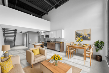 A modern living room with a dining area and a kitchen in the background.at Plant 1 Lofts, N. Newton, IA 50208  